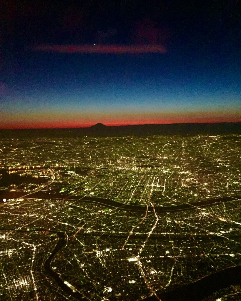 飛行機の窓から東京の夜景と富士山